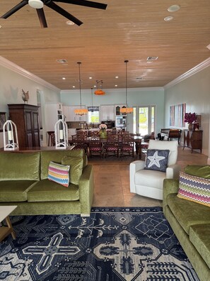 A spacious living area with a high ceiling, a dining area, and a kitchen.