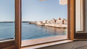 Vista desde una ventana que da a una masa de agua, con un complejo de edificios históricos a lo lejos.