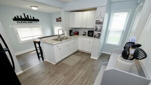 A modern kitchen with white cabinets, a stainless steel sink, and a coffee maker.