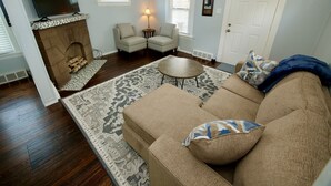 A living room with a fireplace, a television, two armchairs, a sofa, and a coffee table.