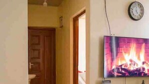 Ein Zimmer mit Kamin, einer Wanduhr und einer Tür zu einem weiteren Raum.
