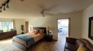 Relax in this serene bedroom with a large bed, ceiling fan, and comfortable armchair.