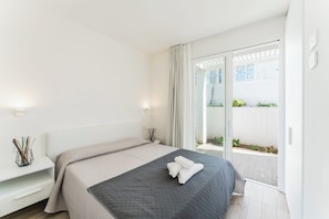 A modern bedroom with a bed, bedside tables, and a view of a balcony.