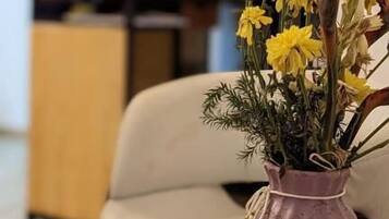 A living room with a purple vase of yellow flowers on a round wooden table.
