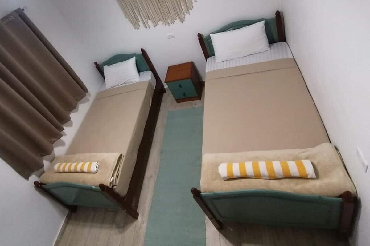 A room with two single beds, a small table, and a curtain.
