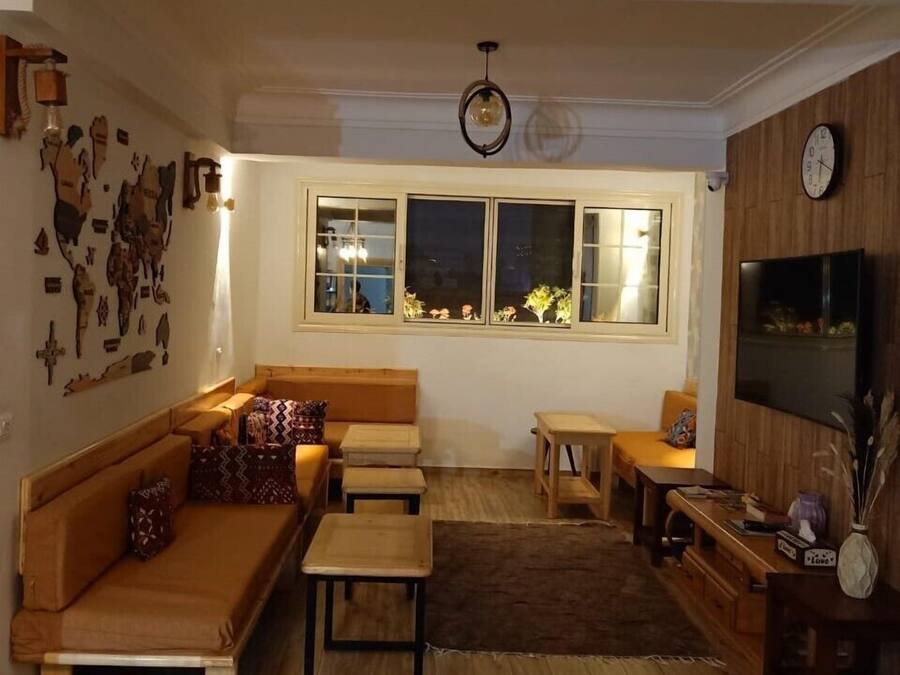 Una sala de estar acogedora con un sofá, una mesita, un televisor y una ventana con vista al cielo nocturno.