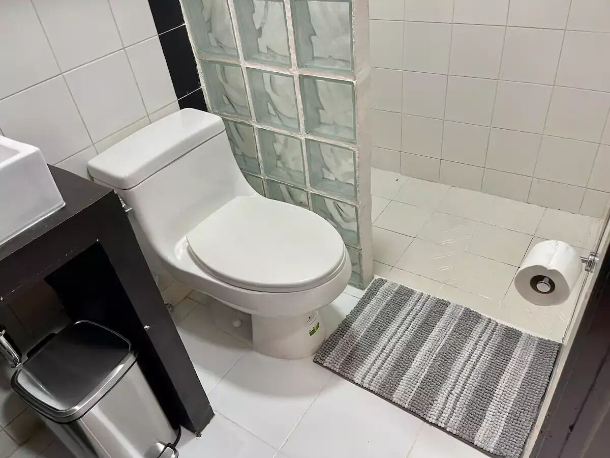 A bathroom with a toilet, a shower area, and a small sink.