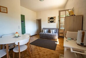 Un ambiente compatto con angolo ristoro, divano e angolo cottura.