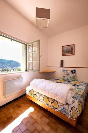 Una camera da letto con un letto, una finestra vista, un termosifone e un quadro appeso al muro.