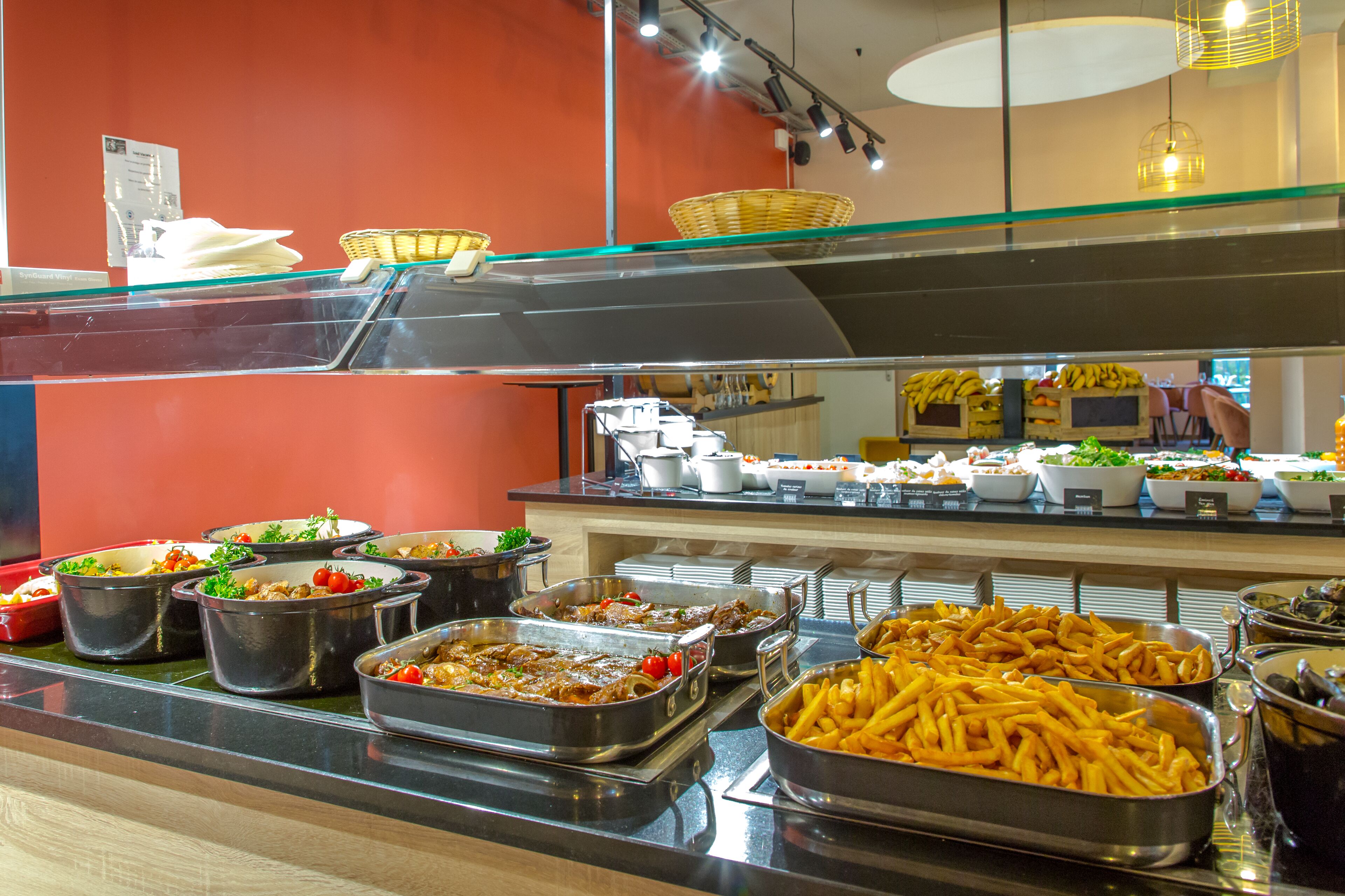 A buffet with various food options including salads, pasta, and French fries.