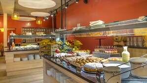 Un área de bufé con diferentes opciones de comida y una barra con platos y tazones.