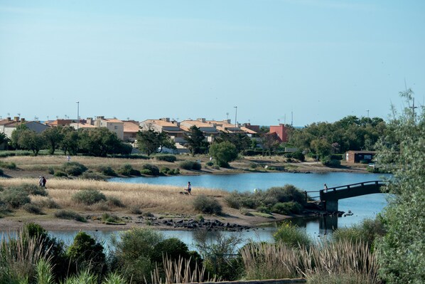 A riverside view with a bridge, buildings, and greenery. - SOWELL HÔTELS Les Jardins du Cap (Agde)
