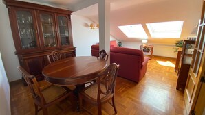 A dining area with a wooden table and chairs, a red sofa, and a cabinet with glass doors.