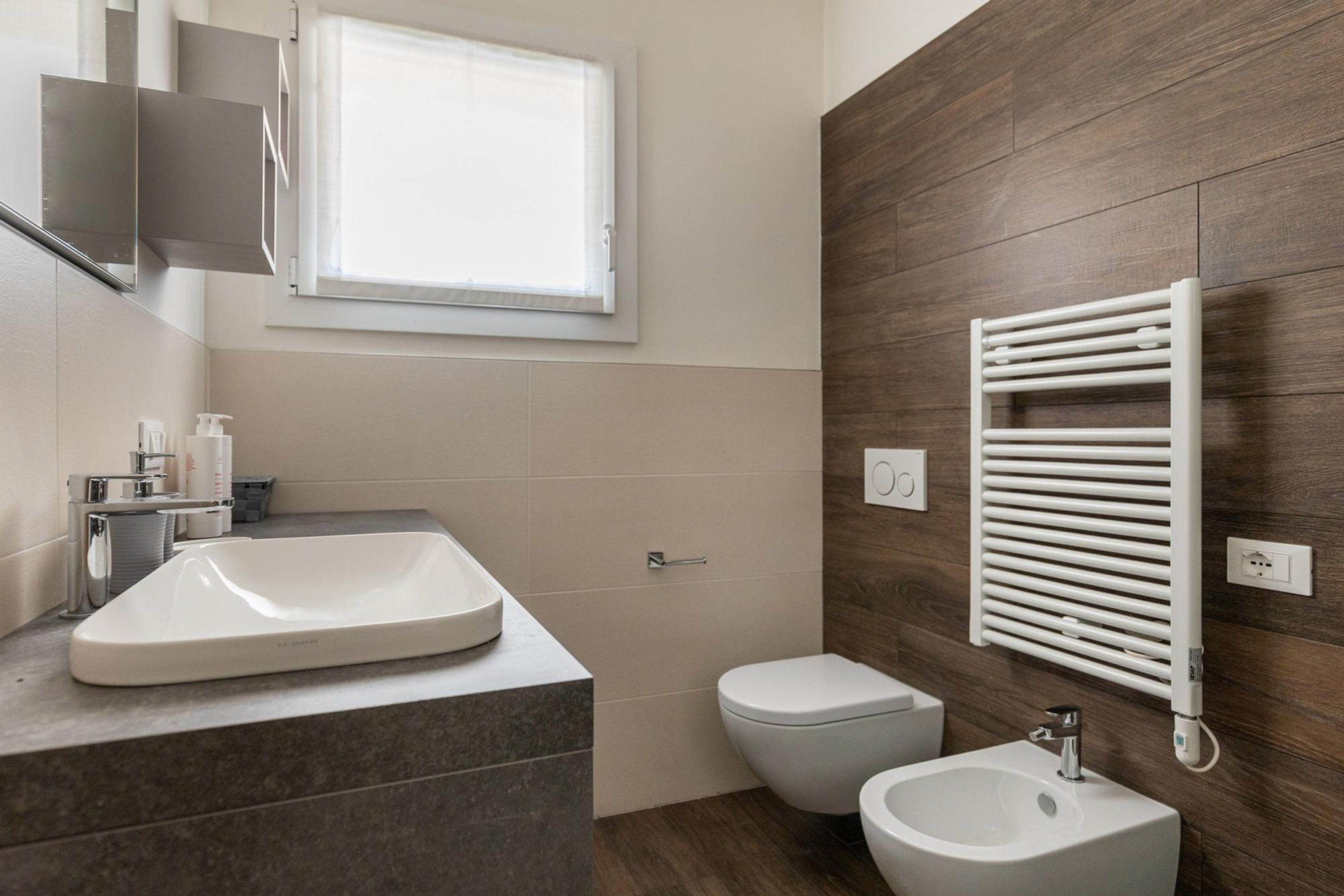 A modern bathroom with a large sink, a toilet, and a bidet.