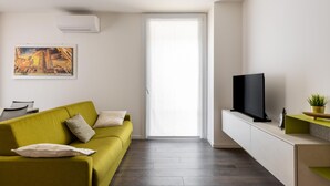 Ein modernes Wohnzimmer mit einem grünen Sofa, einem Flachbildfernseher und einem Bild an der Wand.