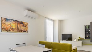 Ein modernes Wohnzimmer mit Esstisch, einer Couch, einem Fernseher und einem Bücherregal.
