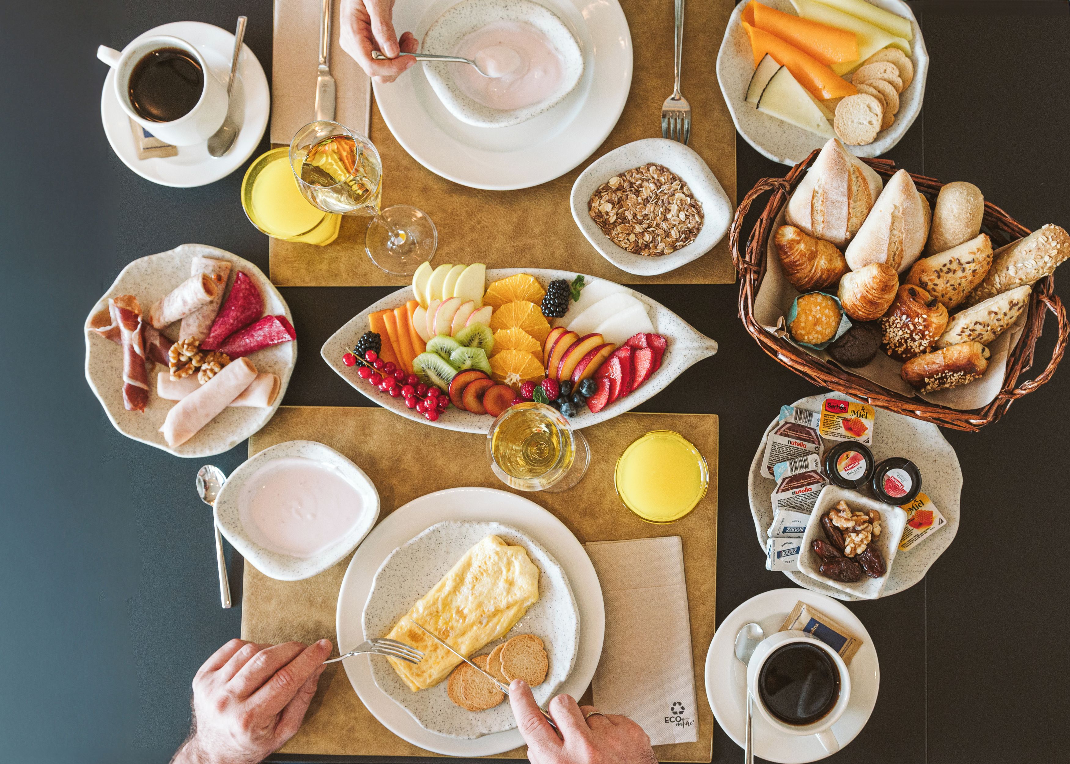 Una mesa con diferentes alimentos, platos y utensilios, que sugiere un ambiente para comer.