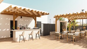 An outdoor patio area with a wooden pergola, a bar with stools, and a seating area with tables and chairs.