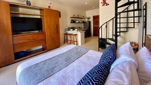 A bedroom with a bed, a TV, a wardrobe, a kitchen area, and a spiral staircase. - Lovely Loft In Veleta (Tulum)