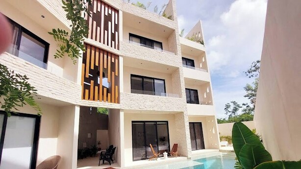 A modern multi-story building with a swimming pool, outdoor seating, and large windows. - Lovely Loft In Veleta (Tulum)