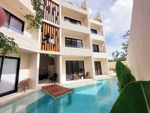 A modern multi-story building with a swimming pool, outdoor seating, and large windows. - Lovely Loft In Veleta (Tulum)
