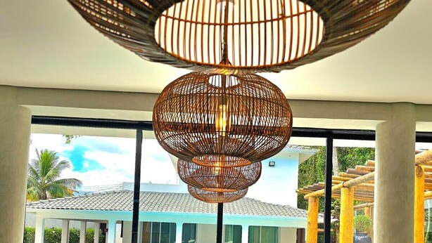 Un interior moderno con un gran ventanal con vistas a una zona de piscina, que presenta una lámpara de fibra óptica original y una mesa de cristal reflectante.