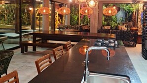 Una cocina moderna con una isla grande, luces colgantes y vistas al verde exterior.
