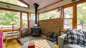 Una habitación acogedora con chimenea, ventanas amplias, una mesa de madera y un sofá.