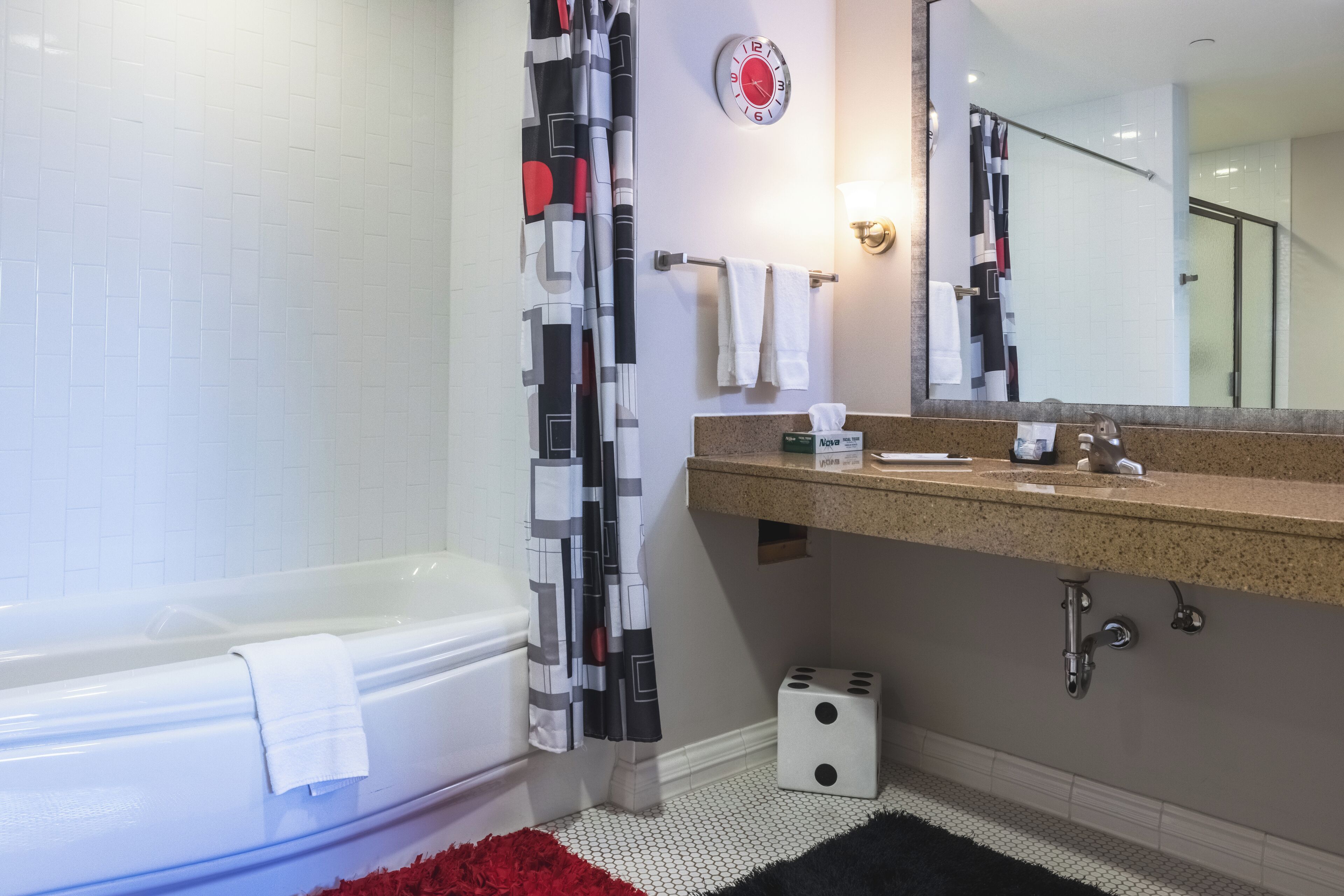 Une salle de bain moderne avec une baignoire, un rideau de douche, un lavabo avec un miroir et un porte-serviettes.