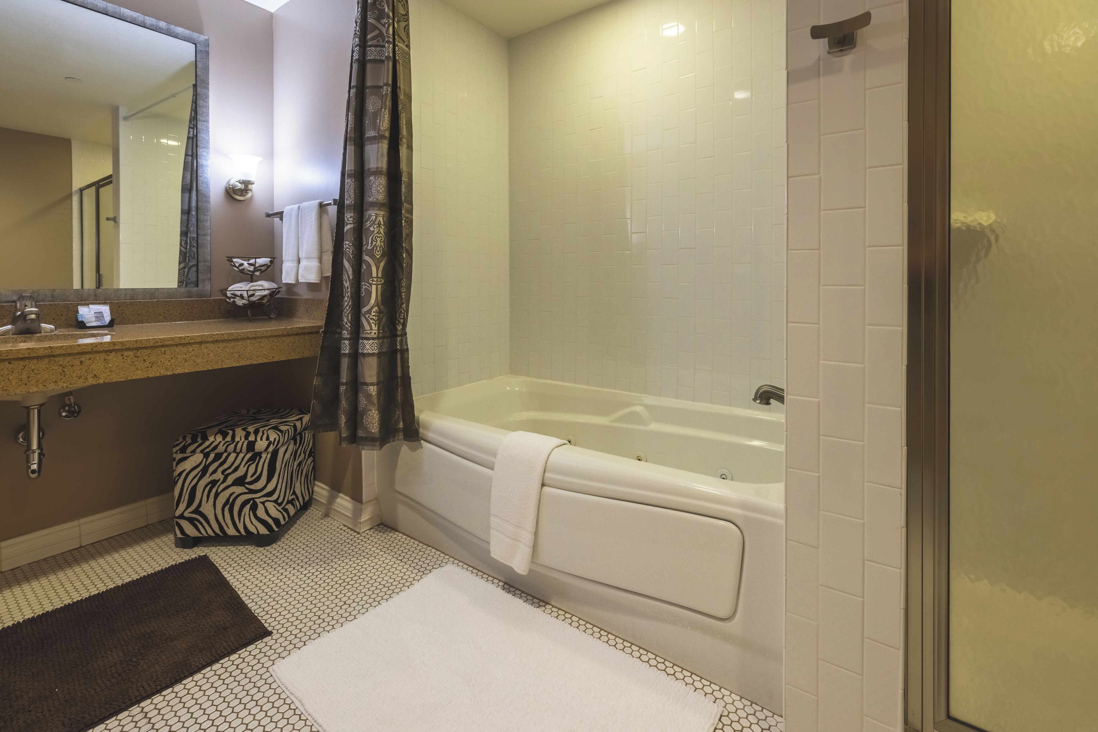Une salle de bain équipée d’une baignoire, d’un lavabo, d’un miroir et d’un espace douche.