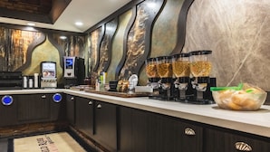 Un bar d’hôtel avec un mur de marbre, une machine à café et un panier de pain.