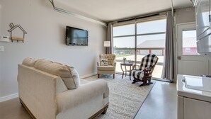 Una sala de estar con un sofá, un sillón y un televisor en la pared.