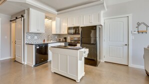 Una cocina moderna con armarios blancos, electrodomésticos de acero inoxidable y una isla central.
