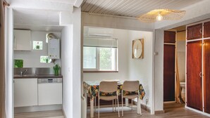 A compact kitchen with white cabinets, a dishwasher, and a dining area with two chairs and a table. - Bungalow U Prato - 100m de la mer (Lumio)