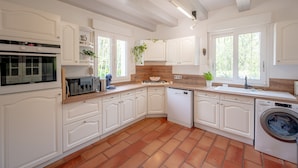 Une cuisine moderne avec des meubles blancs, un four encastré, un lave-vaisselle et un lave-linge.