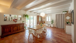 Un vaste espace dédié à la salle à manger, avec une table et des chaises en bois, un buffet en bois et une plante suspendue.
