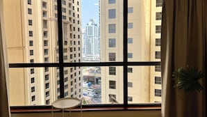 A room with a large window overlooking high-rise buildings and a busy street. - Enjoy and Stay In Dubai Homes (Dubai)