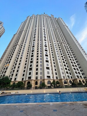 Un grand immeuble moderne, avec de nombreuses étages, et une piscine en premier plan.