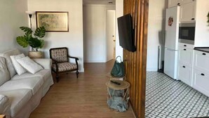 A living room with a sofa, armchair, and a small round table with a plant. A TV is mounted on a wooden panel. - Apartamento Entero Para 4 Personas en Leioa. Sin Ascensor (Leioa)