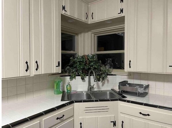 Kitchen with white cabinetry, black handles, and a window above the sink.
