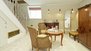 A spacious room with a staircase, a dining table with chairs, a wooden cabinet, and a large mirror.