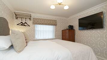 Une chambre à coucher avec un lit, une armoire, une télévision et une fenêtre avec des stores.