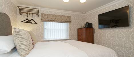 A bedroom with a bed, a wardrobe, a TV, and a window with blinds.