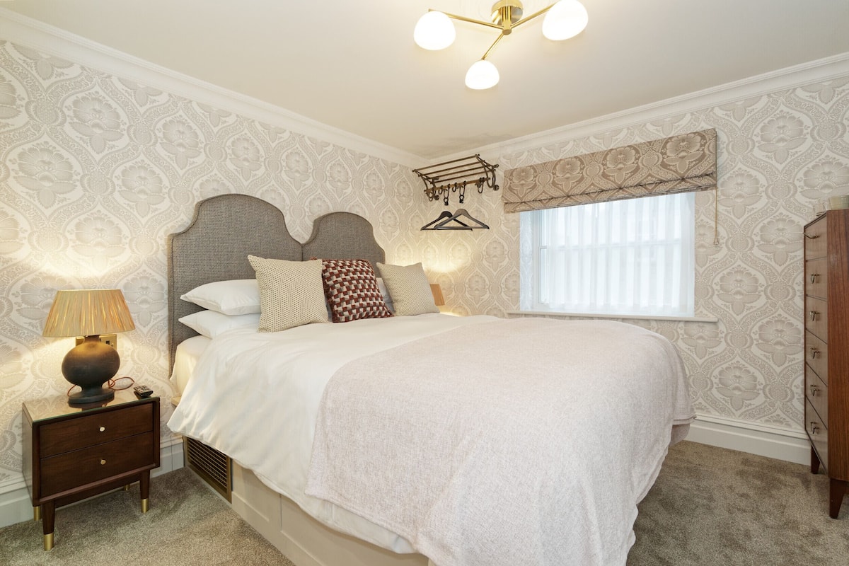 A neatly made bed with a headboard, a bedside lamp, and a wooden nightstand.