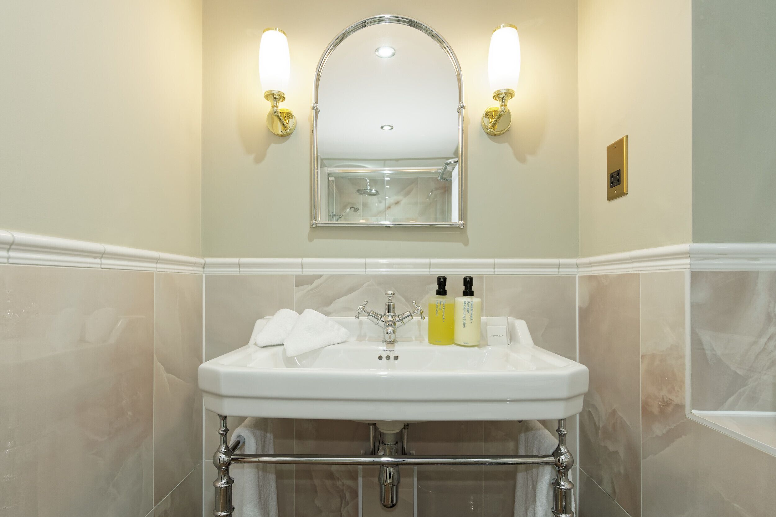 Un bagno con un lavandino bianco, due luci a parete e un grande specchio.