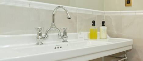 Un baño con lavamanos blanco, accesorios de cromo, toallero y espejo.