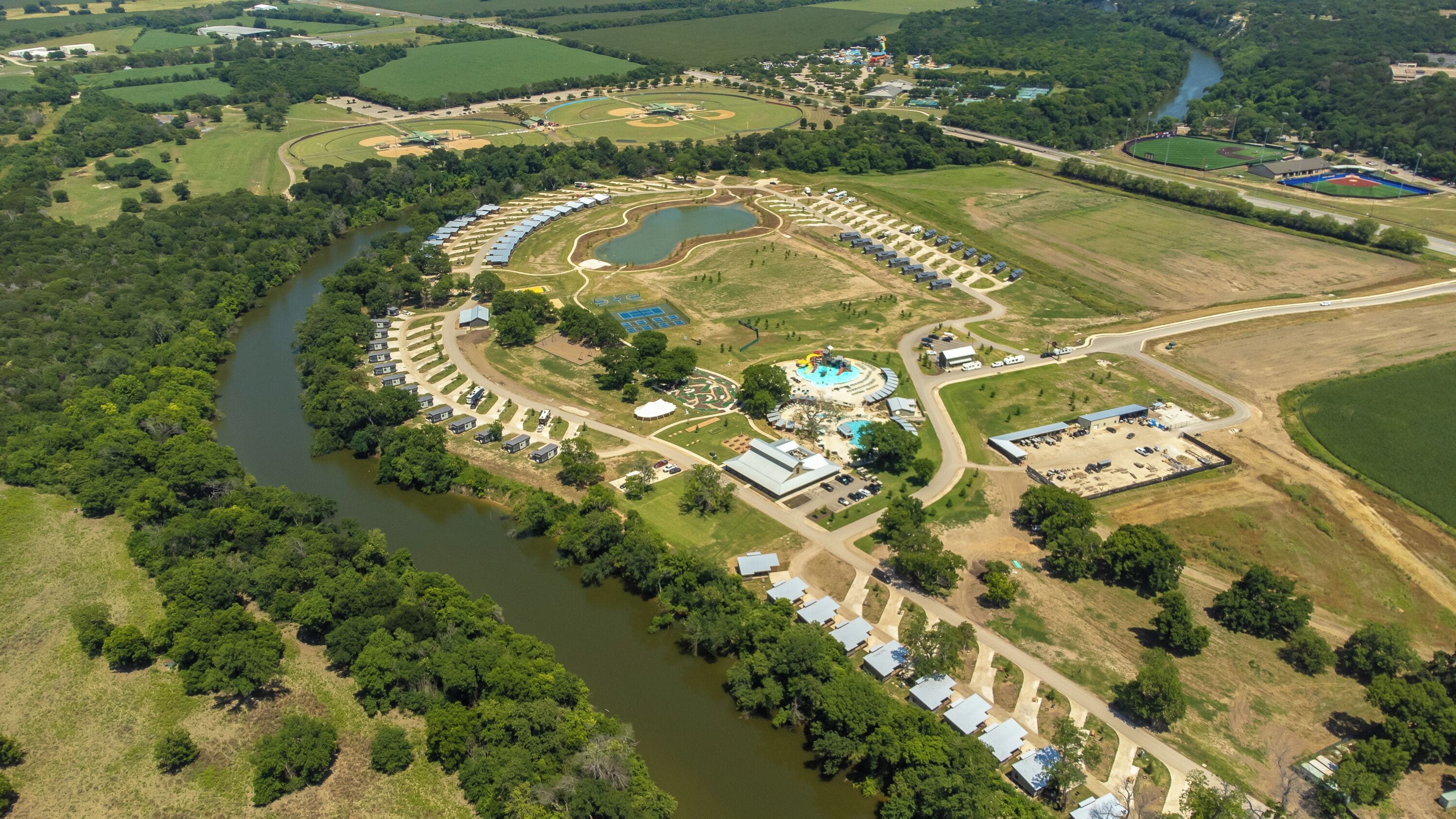 An aerial view of a campground with RV parking, a swimming pool, and a baseball field.