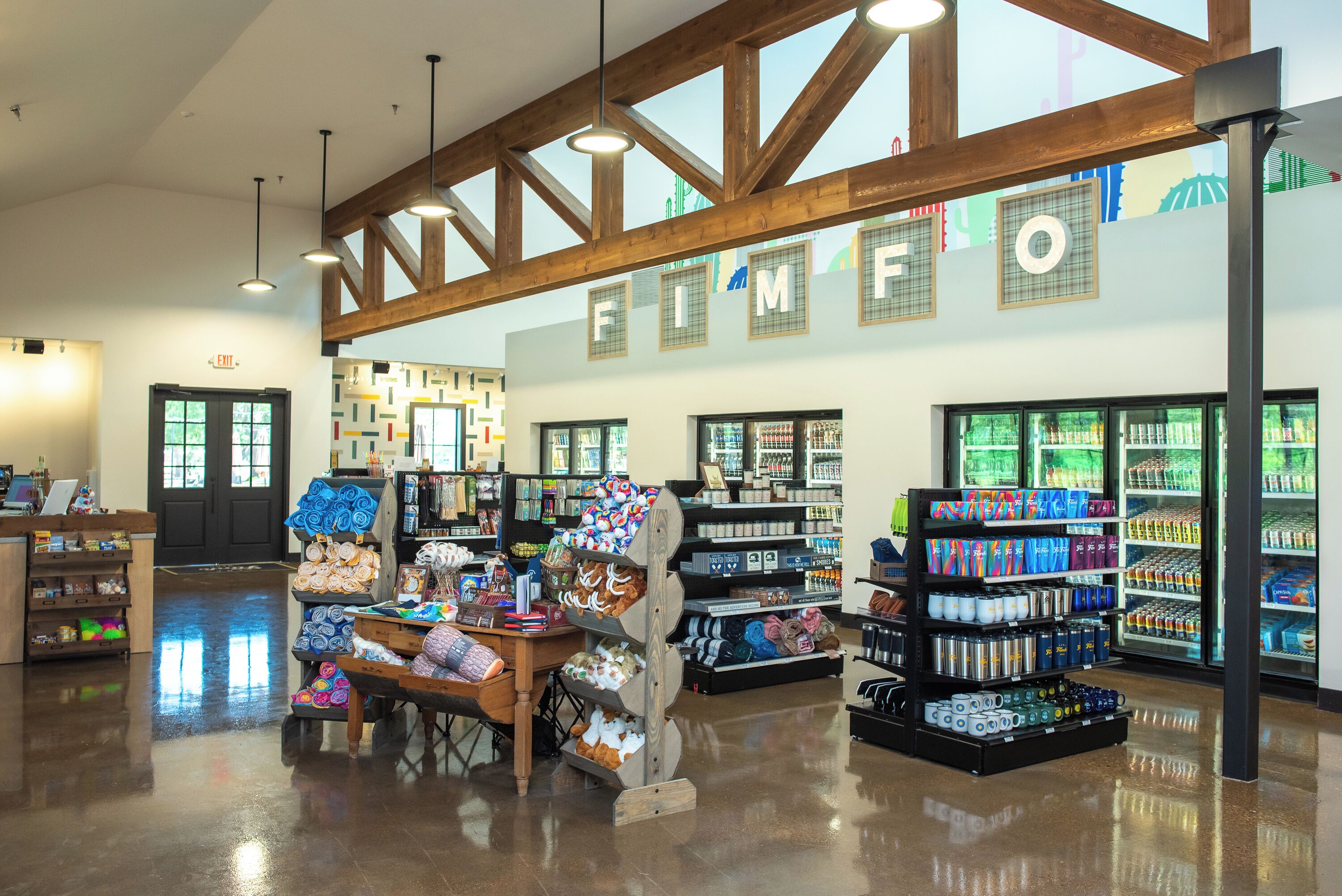 A spacious store with wooden beams, a central display table, and shelves stocked with various products.