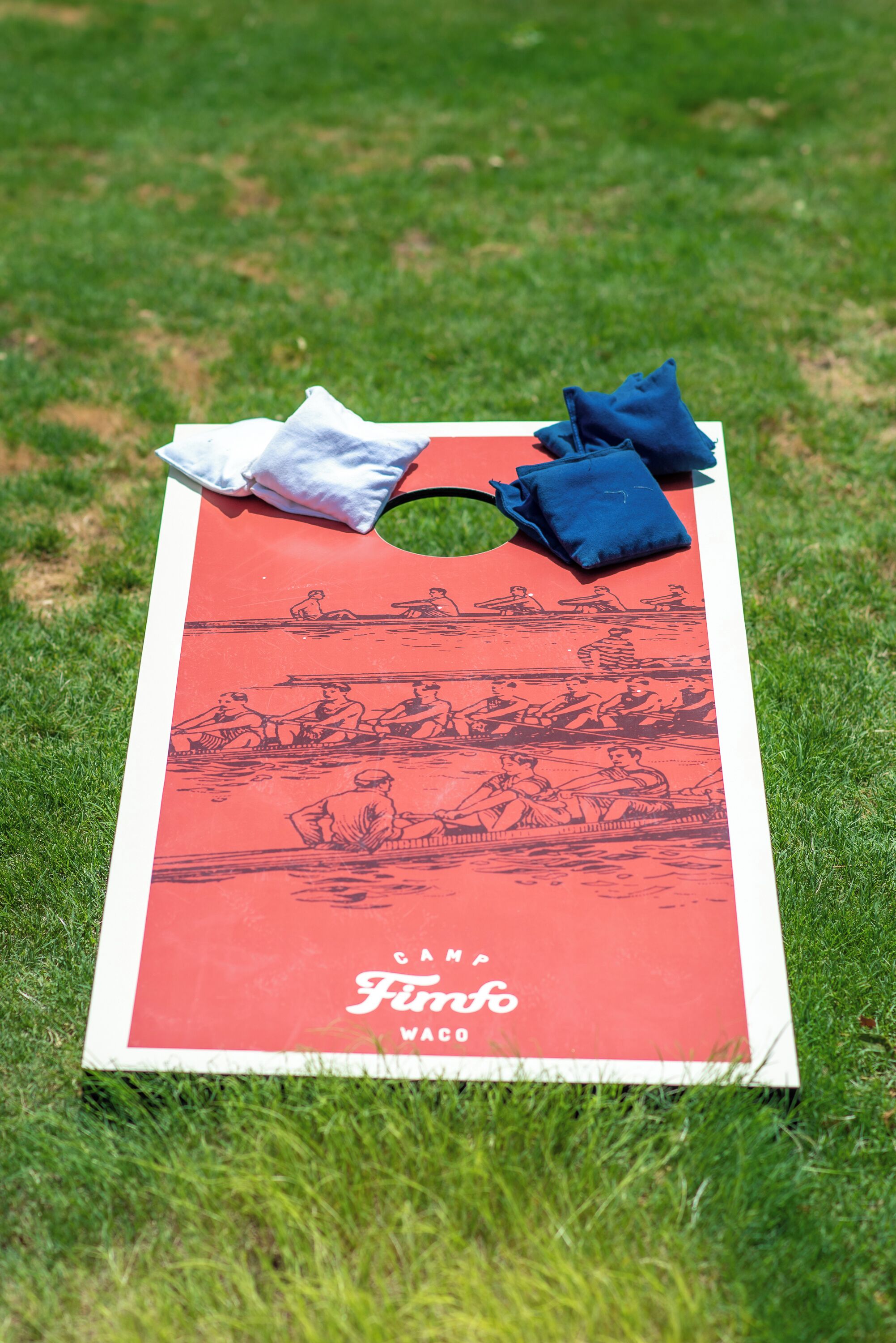 A red and white board game with illustrations of people rowing, placed on grass.