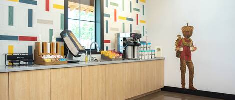 A modern kitchen with a coffee machine, a sink, and a decorative figure.